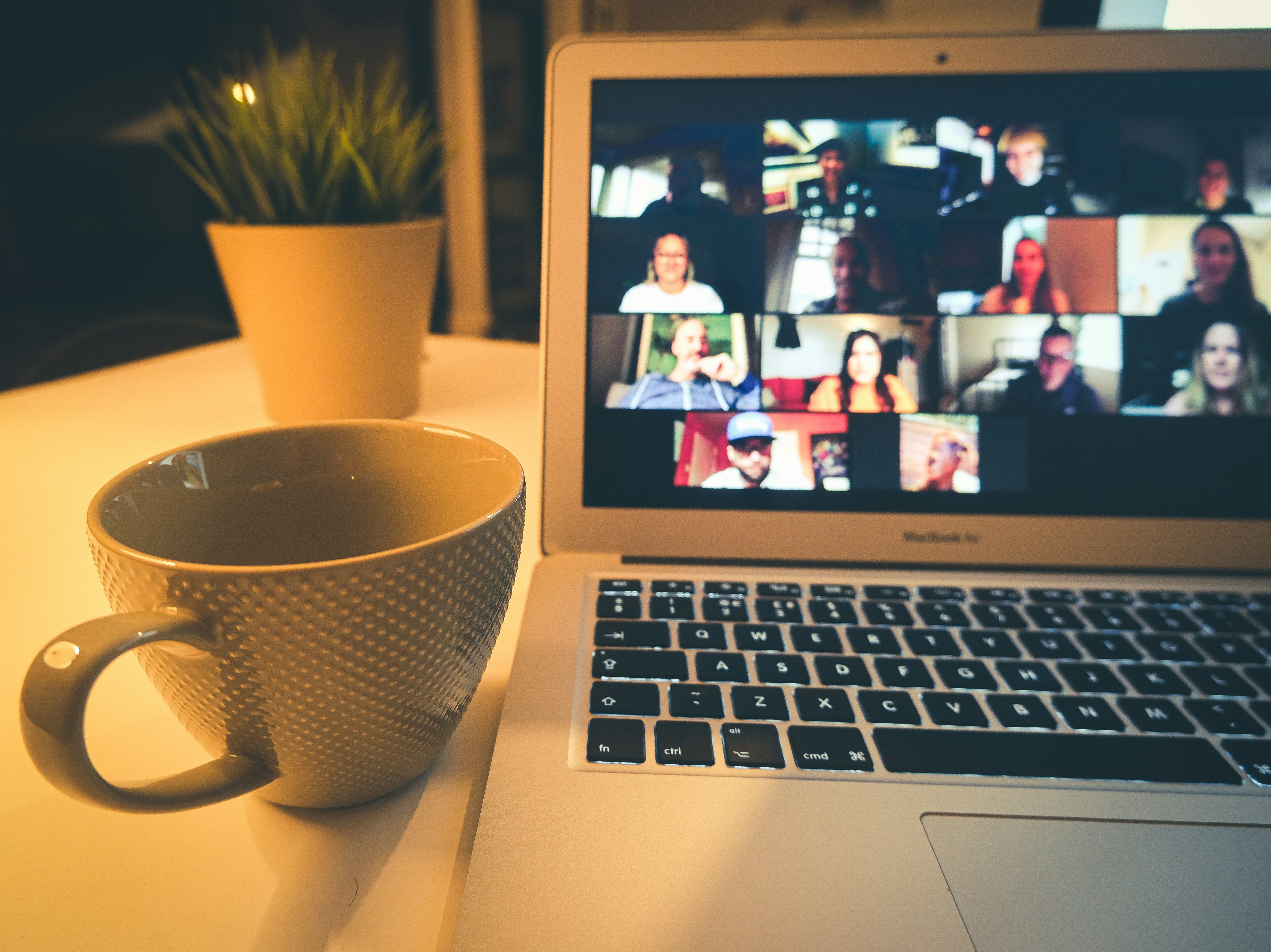 Remote engineering standup — a video call with the cross-functional team on a laptop, design and engineering working from one shared backlog.